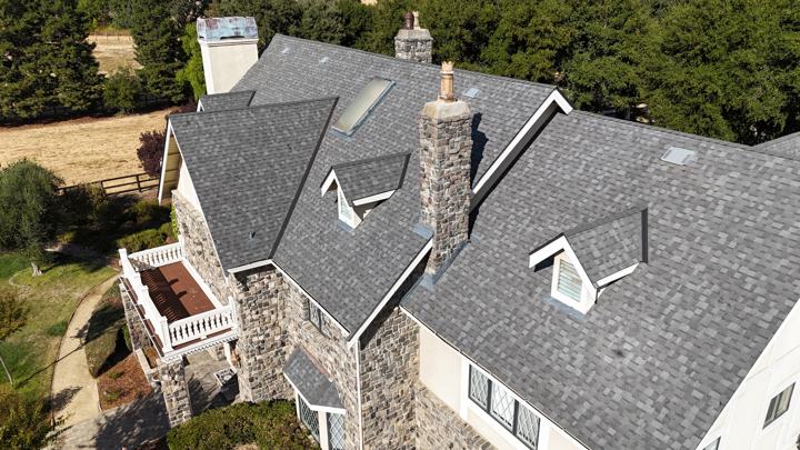 The same stone chimney home, wide by Precise Roofing