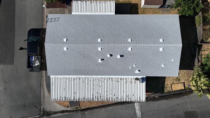 White low slope roof beside metal sections by Precise Roofing