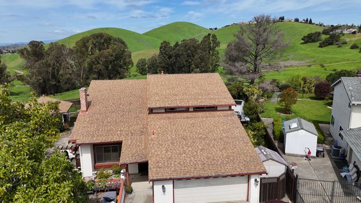 Tan shingles with the hills behind by Precise Roofing